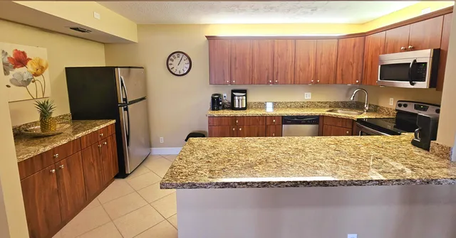 a kitchen with granite countertop a refrigerator stove and wooden cabinets