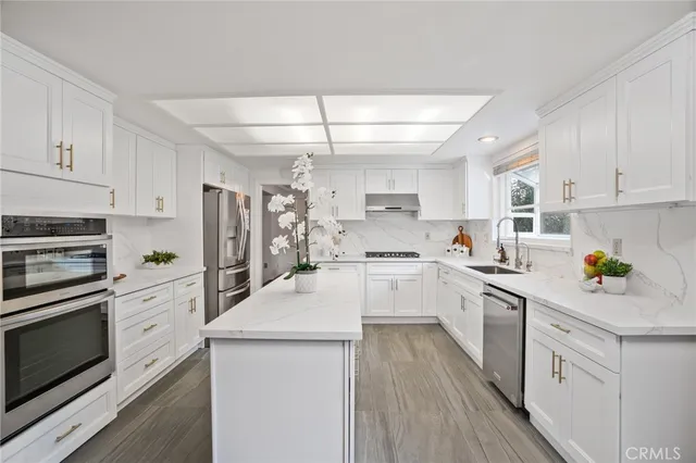 a kitchen with a sink cabinets stainless steel appliances and a window