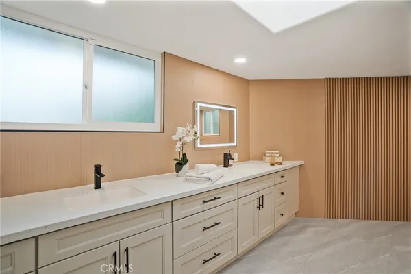 a spacious bathroom with a double vanity sink a mirror a bathtub and a shower