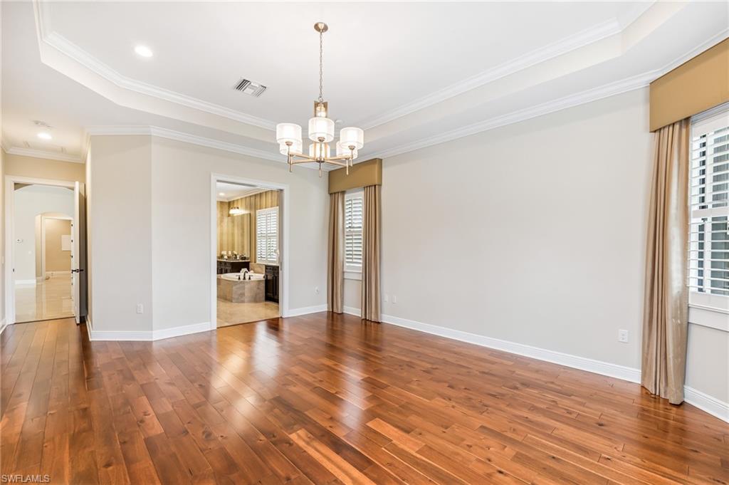 12449 Lockford Lane Naples, FL 34120 - Photo 16 of 45 a view of a hallway with wooden floor and chandelier