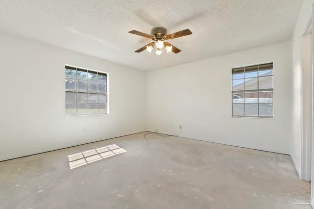 an empty room with windows and fan