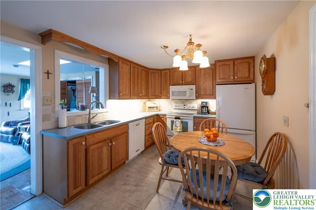 a kitchen with stainless steel appliances granite countertop a dining table chairs and a refrigerator