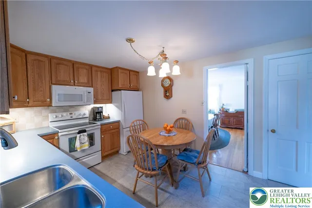 a kitchen with stainless steel appliances granite countertop a stove top oven a sink dishwasher a dining table and chairs with wooden floor