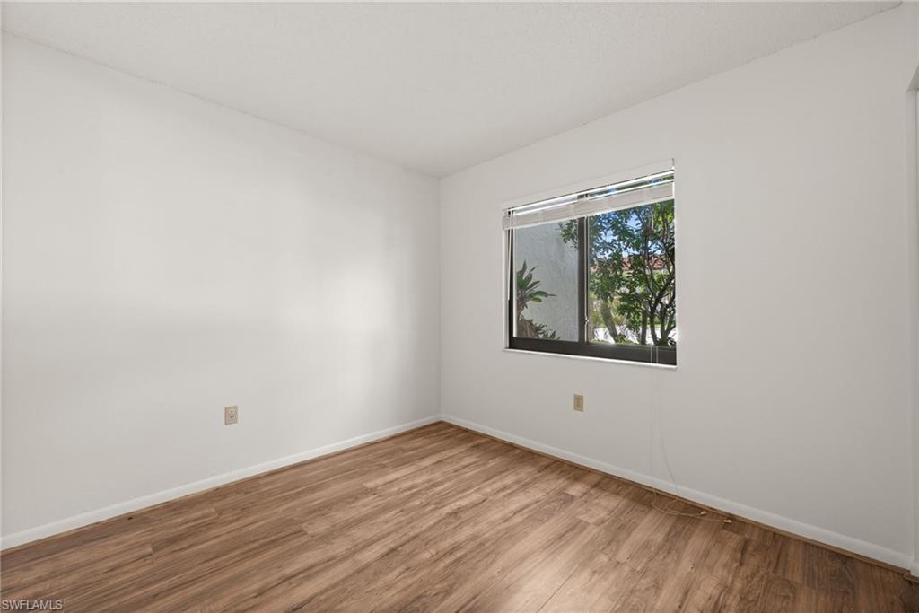 4251 27th Court Southwest, Unit 104 Naples, FL 34116 - Photo 19 of 22 a view of an empty room with wooden floor and a window