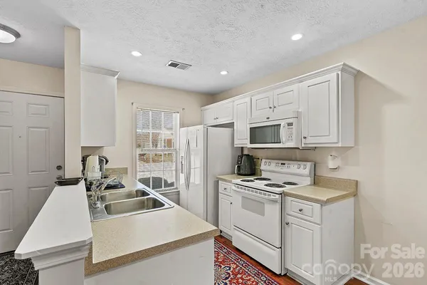 a kitchen that has a lot of white cabinets and stainless steel appliances