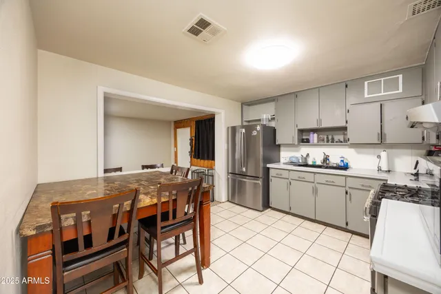 a kitchen with stainless steel appliances a table and chairs in it