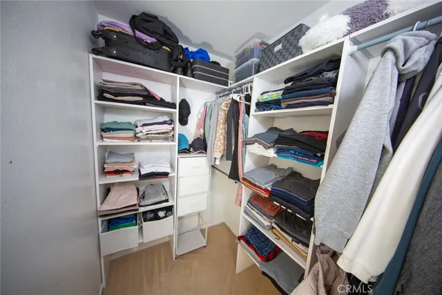 a view of walk in closet with clothes and shoes