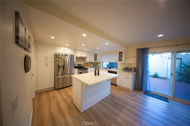 a large kitchen with stainless steel appliances kitchen island a large counter top and a refrigerator