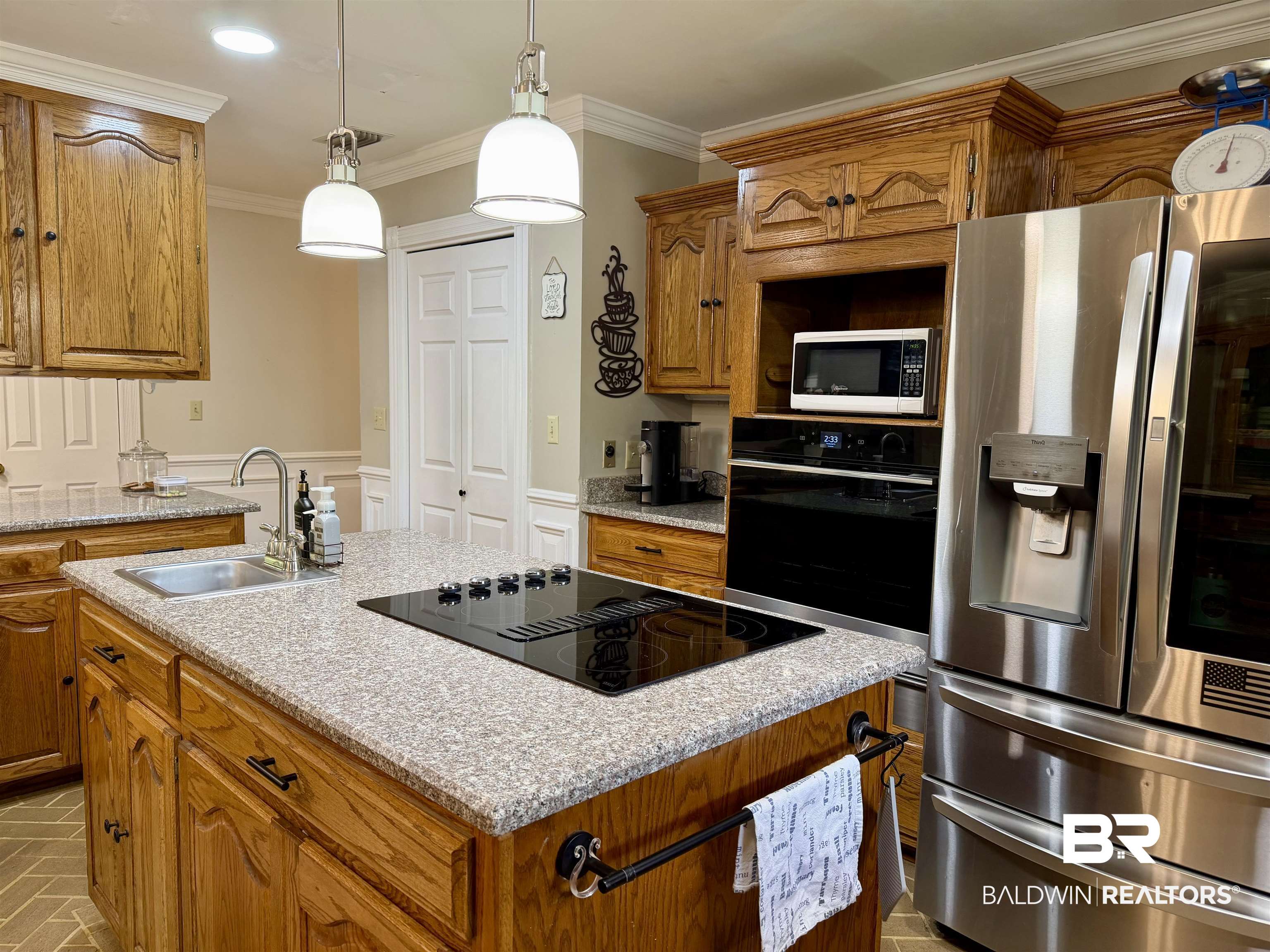 2944 Appleton Road Brewton, AL 36426 - Photo 7 of 65 Kitchen featuring black appliances, a kitchen island with sink, wood finish cabinetry, ornamental molding, and decorative light fixtures