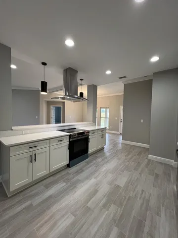 a large kitchen with stainless steel appliances a large counter top a stove and a refrigerator