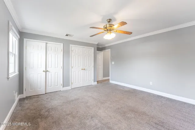 a view of an empty room with chandelier fan and window