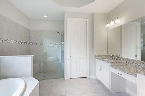 a bathroom with a granite countertop sink a mirror and a bathtub