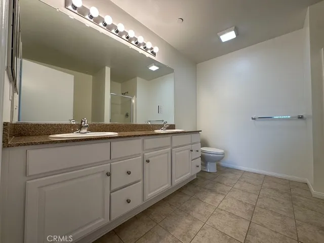 a spacious bathroom with a double vanity sink a toilet and a mirror