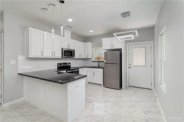 a kitchen with a refrigerator a microwave oven a stove top oven a sink and cabinets