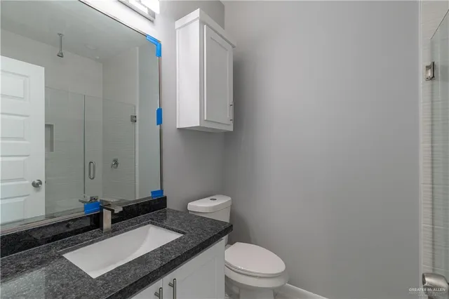 a bathroom with a granite countertop toilet a sink and a mirror