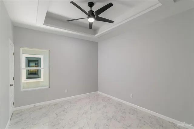 an empty room with a ceiling fan and windows