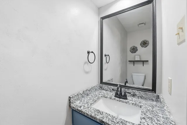 a bathroom with a granite countertop sink and a mirror