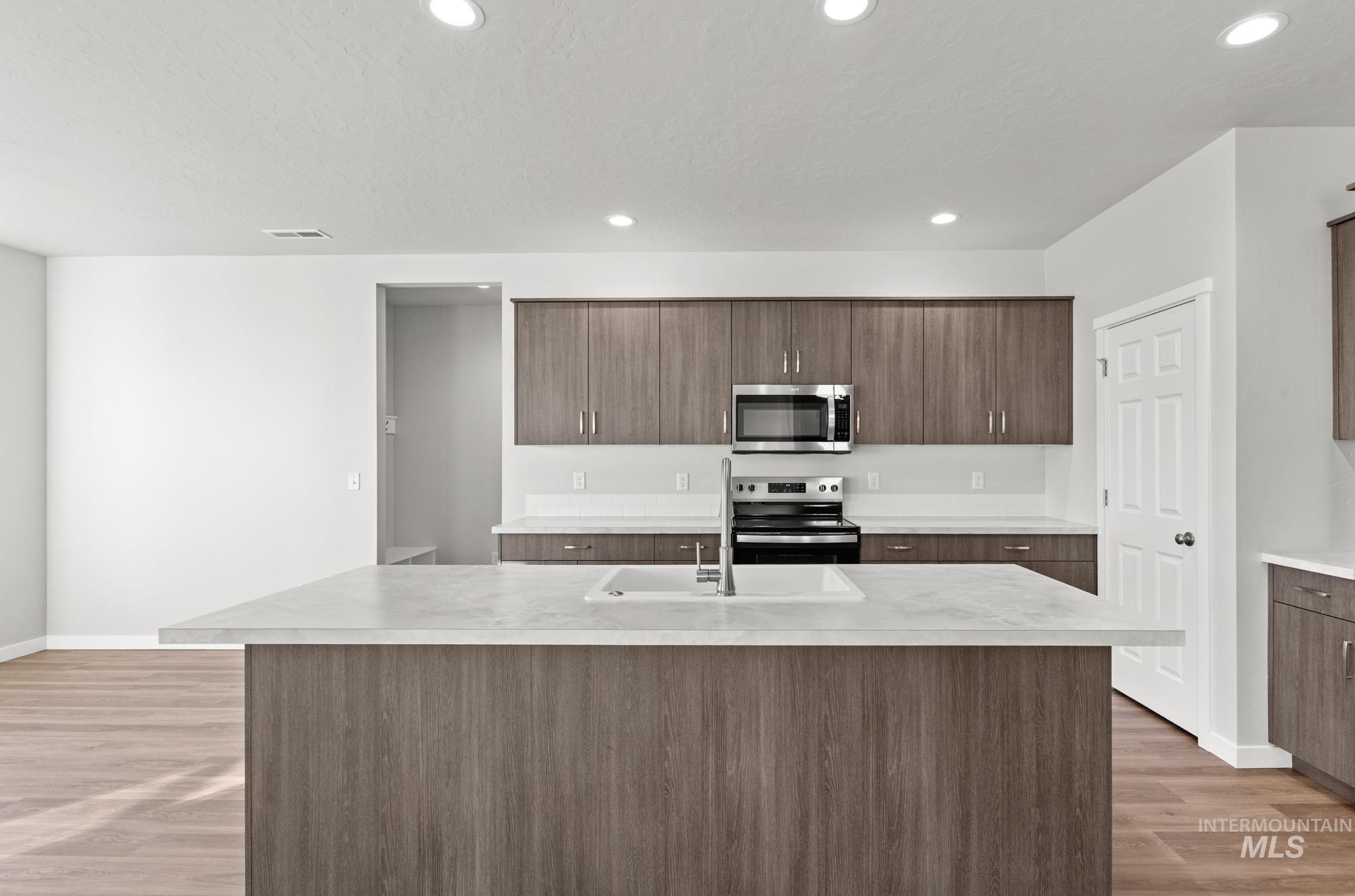 13713 Judson Street Caldwell, ID 83607 - Photo 3 of 24 Kitchen with light countertops, a center island with sink, stainless steel appliances, light wood-style flooring, and modern cabinets