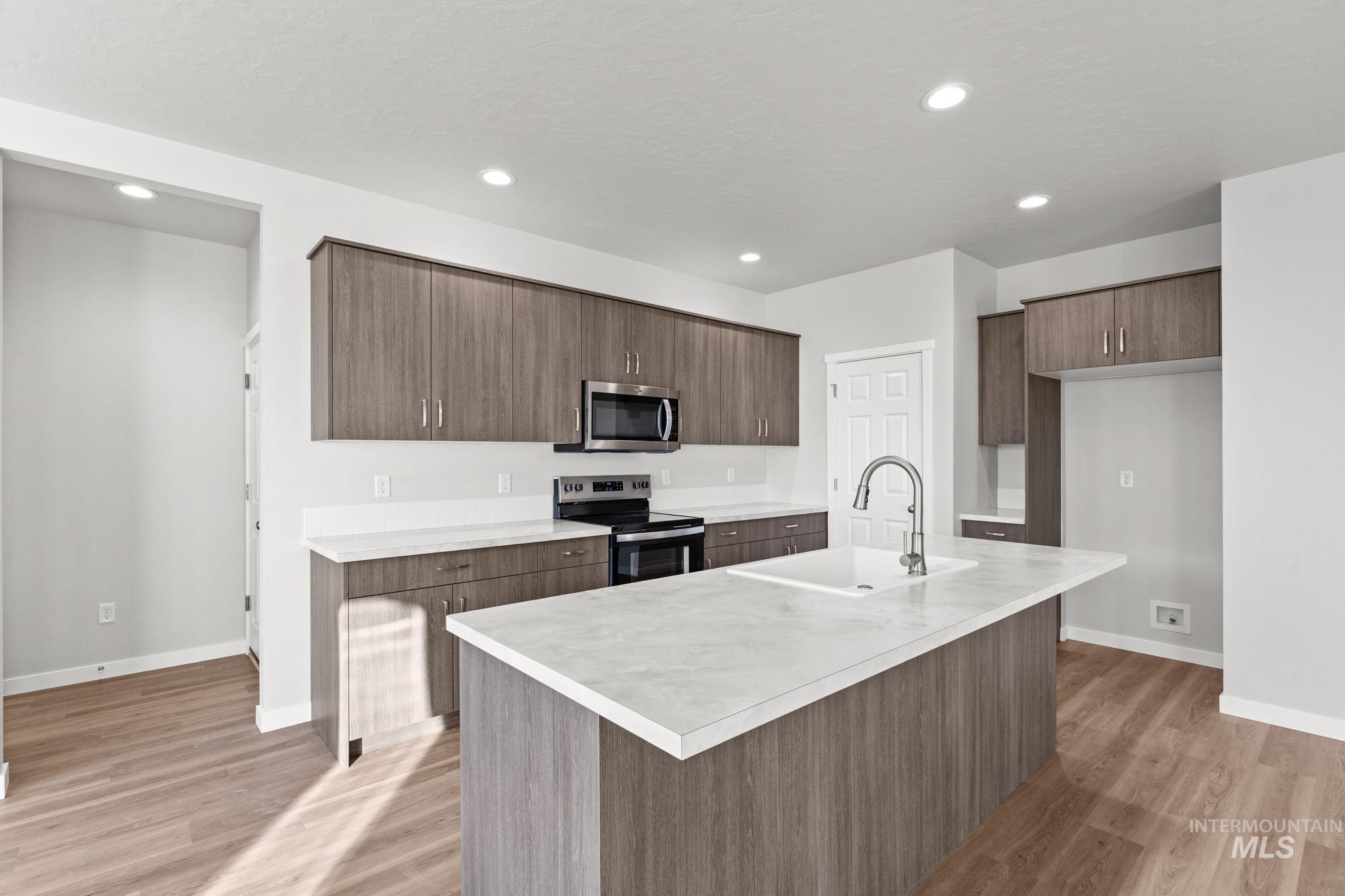 13713 Judson Street Caldwell, ID 83607 - Photo 4 of 24 Kitchen featuring light countertops, stainless steel appliances, light wood-type flooring, an island with sink, and modern cabinets