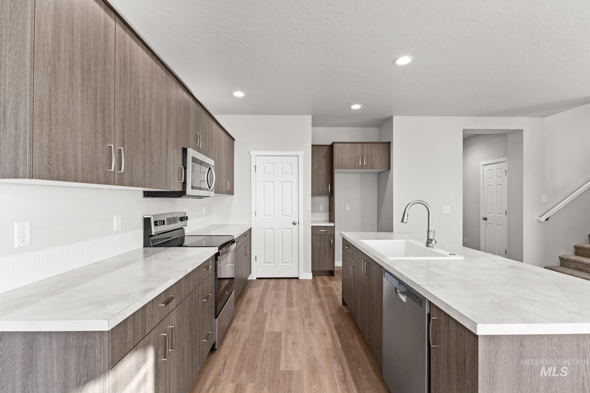 13713 Judson Street Caldwell, ID 83607 - Photo 5 of 24 Kitchen featuring stainless steel appliances, light countertops, light wood-style floors, an island with sink, and recessed lighting