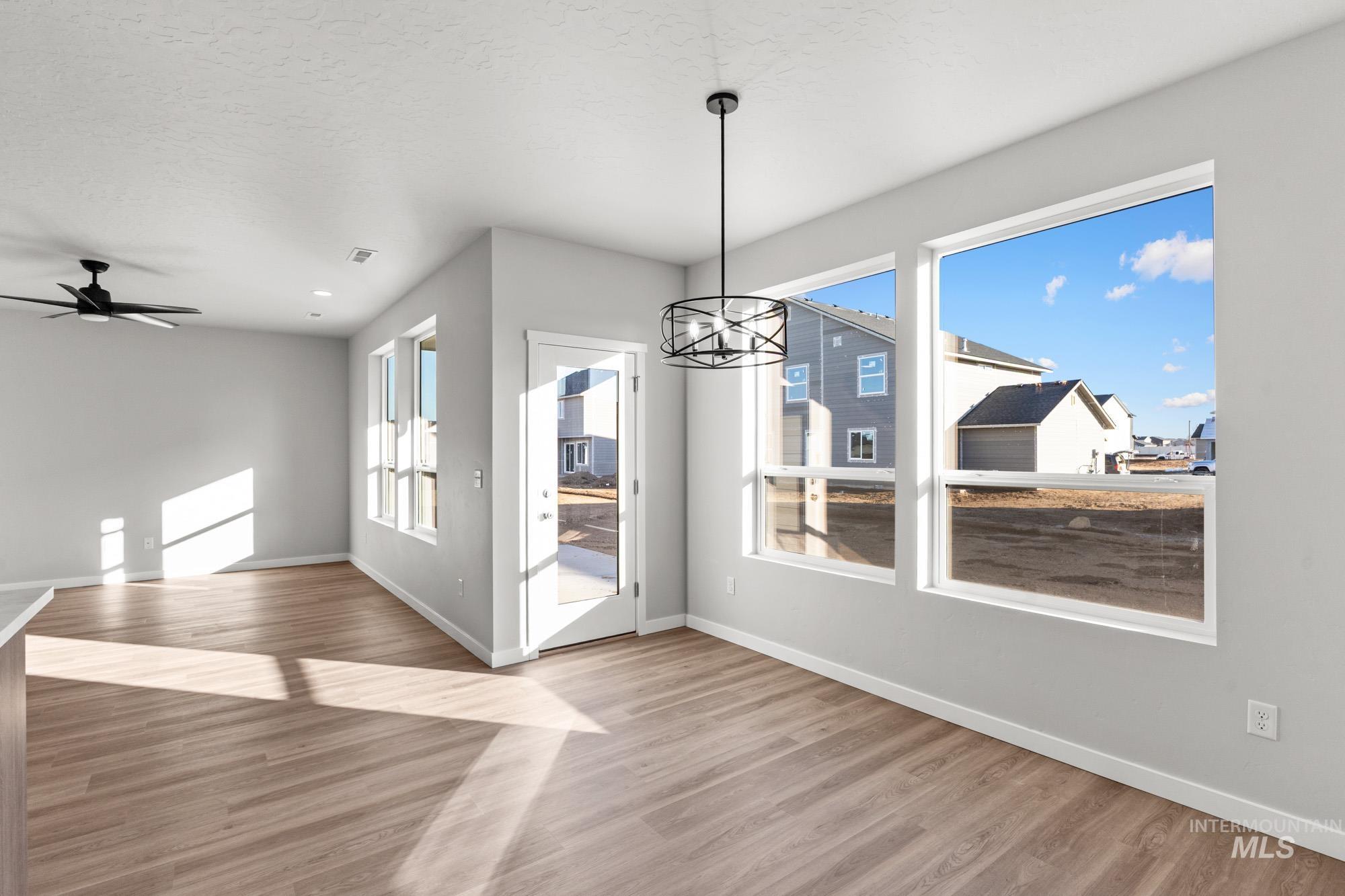 13713 Judson Street Caldwell, ID 83607 - Photo 6 of 24 Unfurnished dining area featuring suspended lighting, ceiling fan, light wood finished floors, healthy amount of natural light, and a textured ceiling