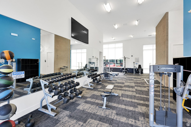 7713 Navarro View Court Midvale, UT 84047 - Photo 39 of 41 Fitness center featuring extensive mirrored walls, a mounted flat-screen display, high ceilings with flush lighting, and large windows with privacy blinds