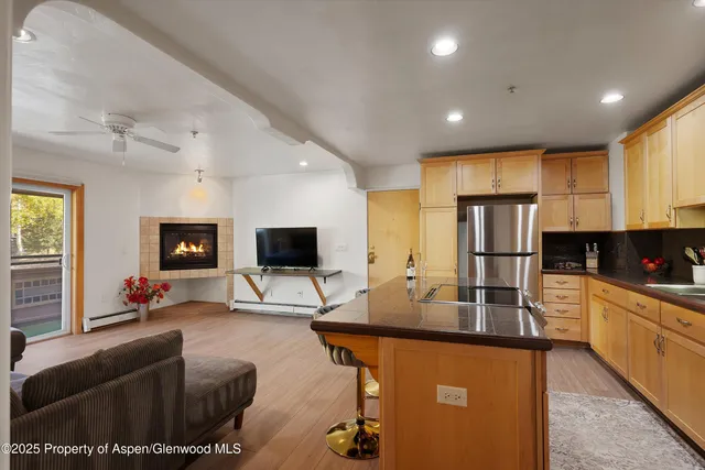 a living room with stainless steel appliances furniture a flat screen tv and a window