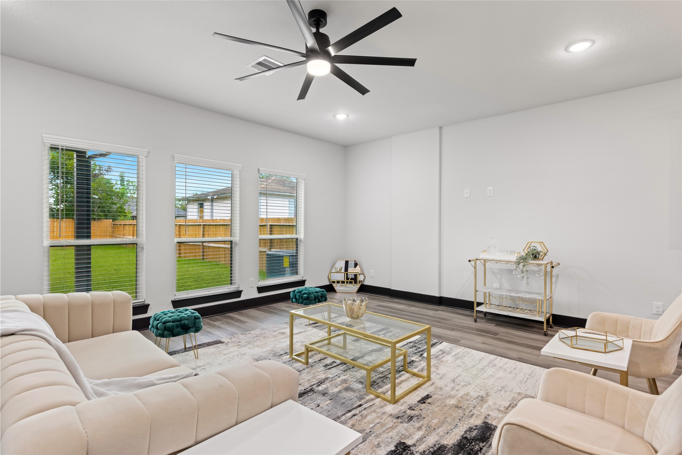 4435 Maggie Street, Unit B Houston, TX 77051 - Photo 10 of 37 Bright living room includes a modern design with large windows for natural light, and a ceiling fan. The space includes stylish furnishings and a view of the fenced backyard. Furnishing can be included!