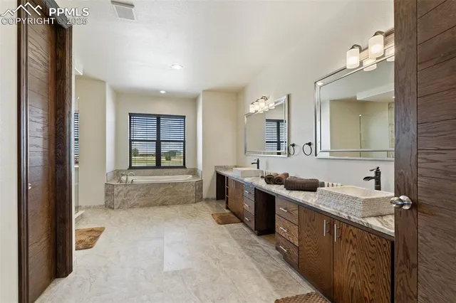 a large bathroom with a granite countertop tub a double vanity sink a vanity and a large mirror