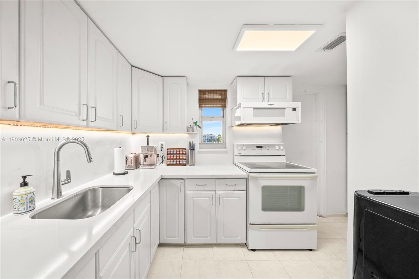 1674 Bay Road, Unit 401 Miami Beach, FL 33139 - Photo 12 of 33 a kitchen with white cabinets and white appliances