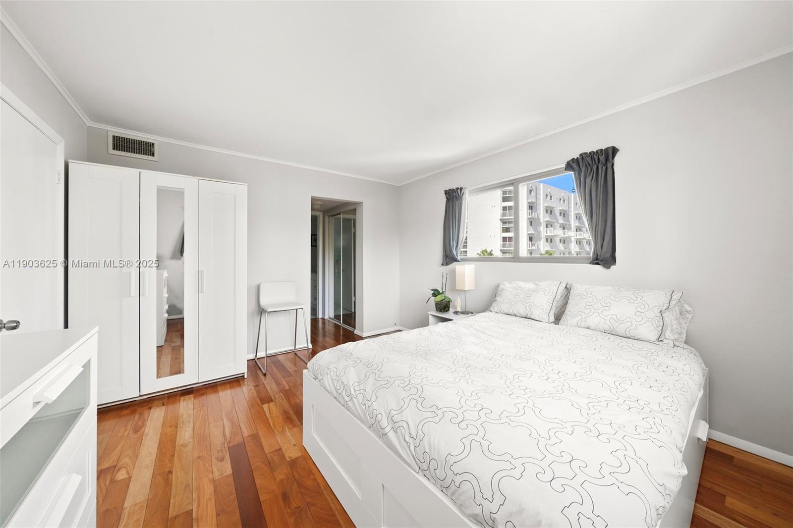 1674 Bay Road, Unit 401 Miami Beach, FL 33139 - Photo 18 of 33 a spacious bedroom with a large bed and a chandelier