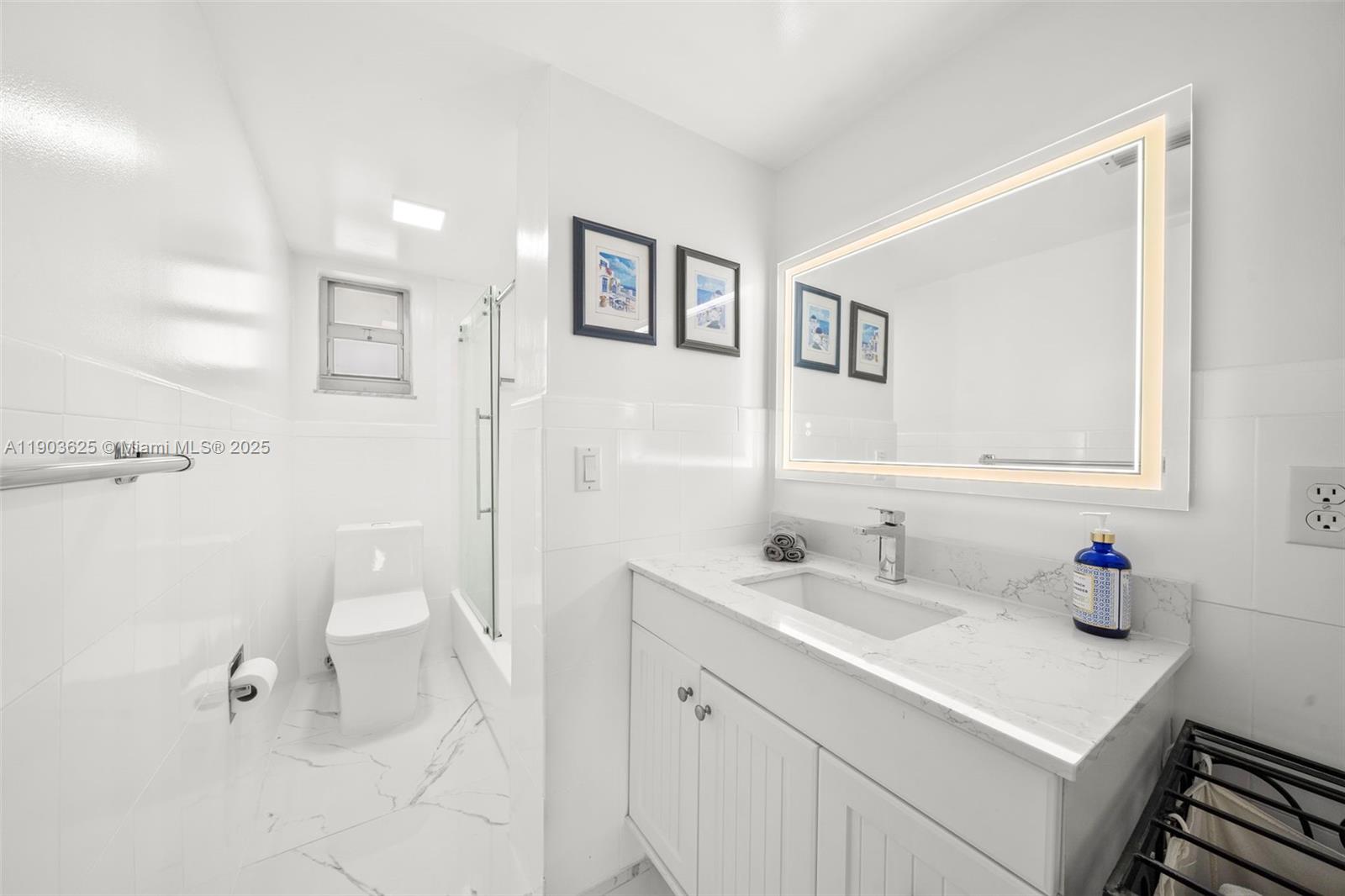 1674 Bay Road, Unit 401 Miami Beach, FL 33139 - Photo 24 of 33 a bathroom with a sink a toilet and a mirror