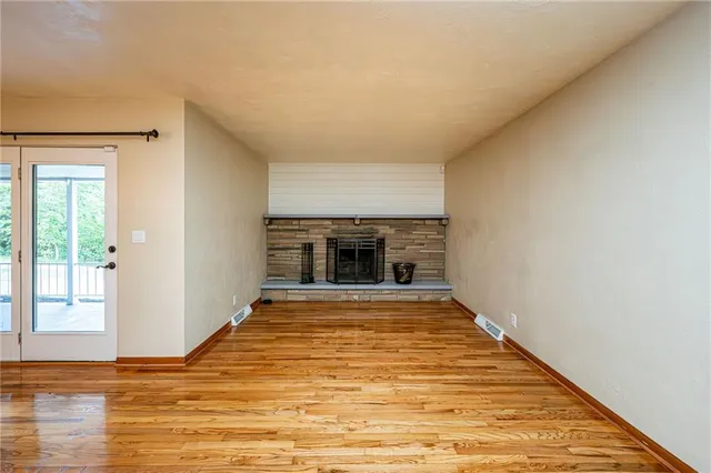 a view of empty room with wooden floor and fireplace