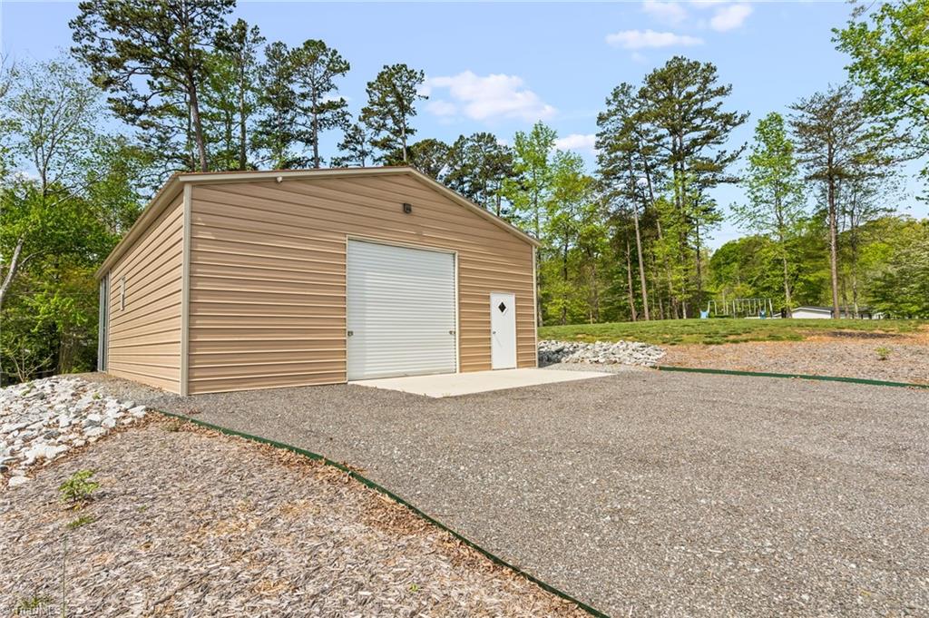 311 Reynolds Road Lexington, NC 27292 - Photo 24 of 32 Front of storage building with wide rollup garage door & entrance door, & interior space for pontoon, jet skis & more lake toys, flawn mowers, and much more!