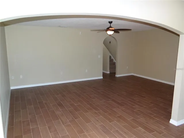 a view of a hallway with wooden floor and a chandelier fan