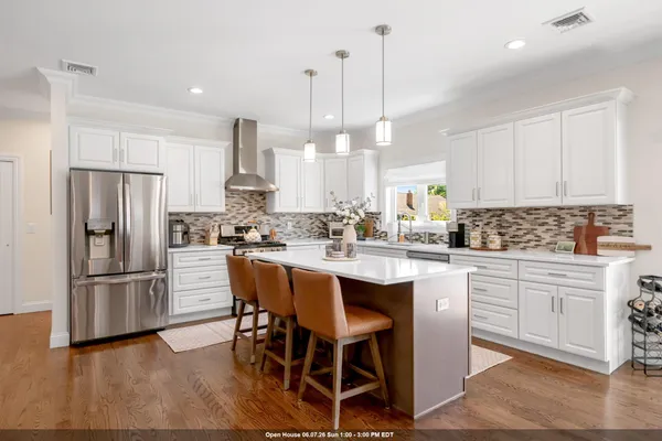 a kitchen with stainless steel appliances a dining table chairs stove and white cabinets