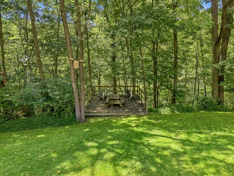 1168 Mt Pleasant Road Bangor, PA 18013 - Photo 20 of 100 Mature trees frame a peaceful wooden deck nestled in a grassy backyard.