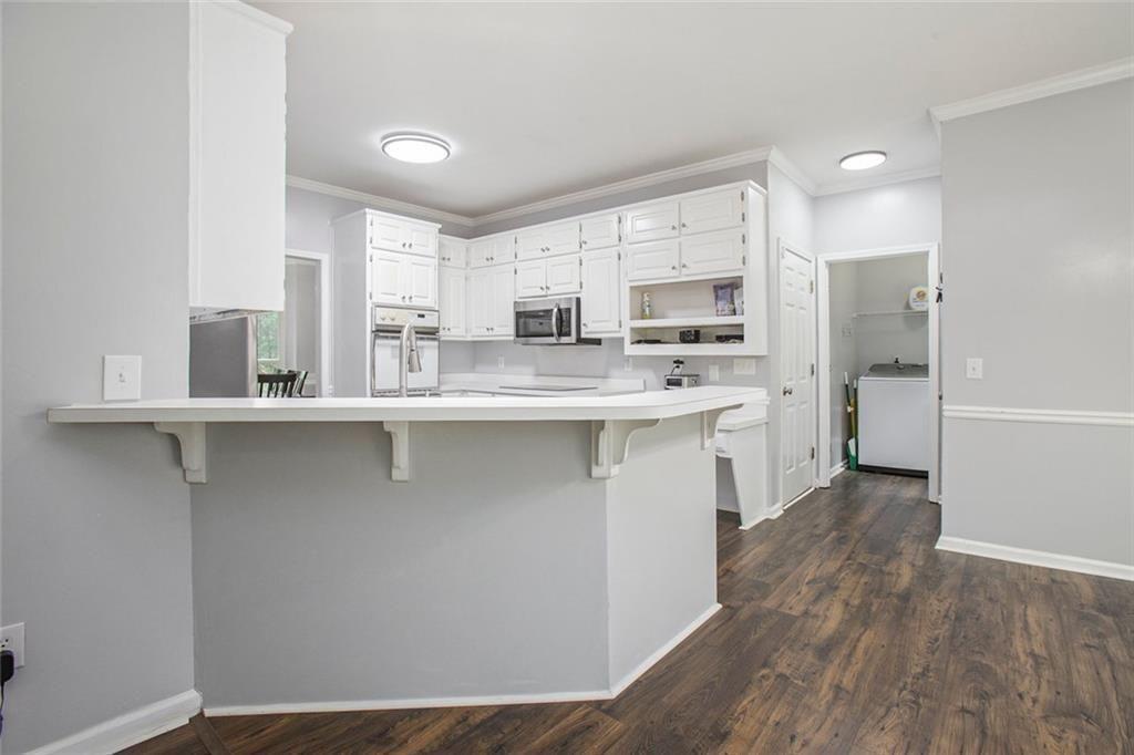 2482 Windchase Court Buford, GA 30518 - Photo 11 of 36 a kitchen with stainless steel appliances granite countertop a stove a sink and white cabinets with wooden floor