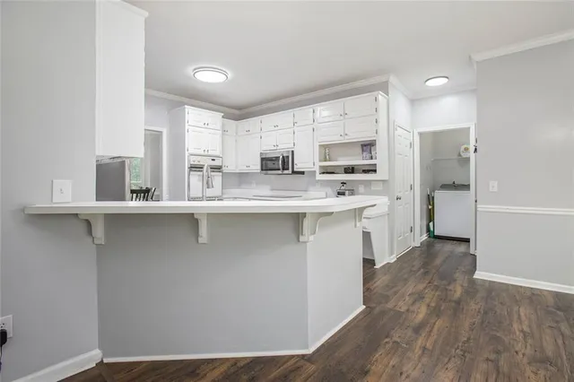 a kitchen with stainless steel appliances granite countertop a stove a sink and white cabinets with wooden floor