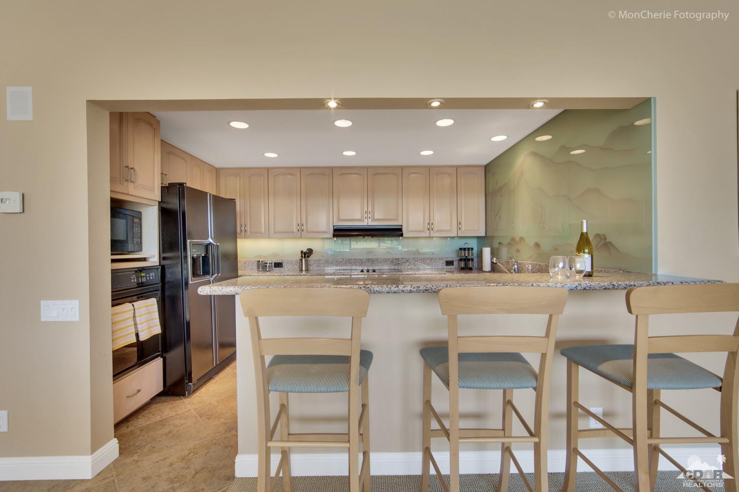 910 Island Drive, Unit 211 Rancho Mirage, CA 92270 - Photo 3 of 38 a kitchen with kitchen island cabinets and chairs in it