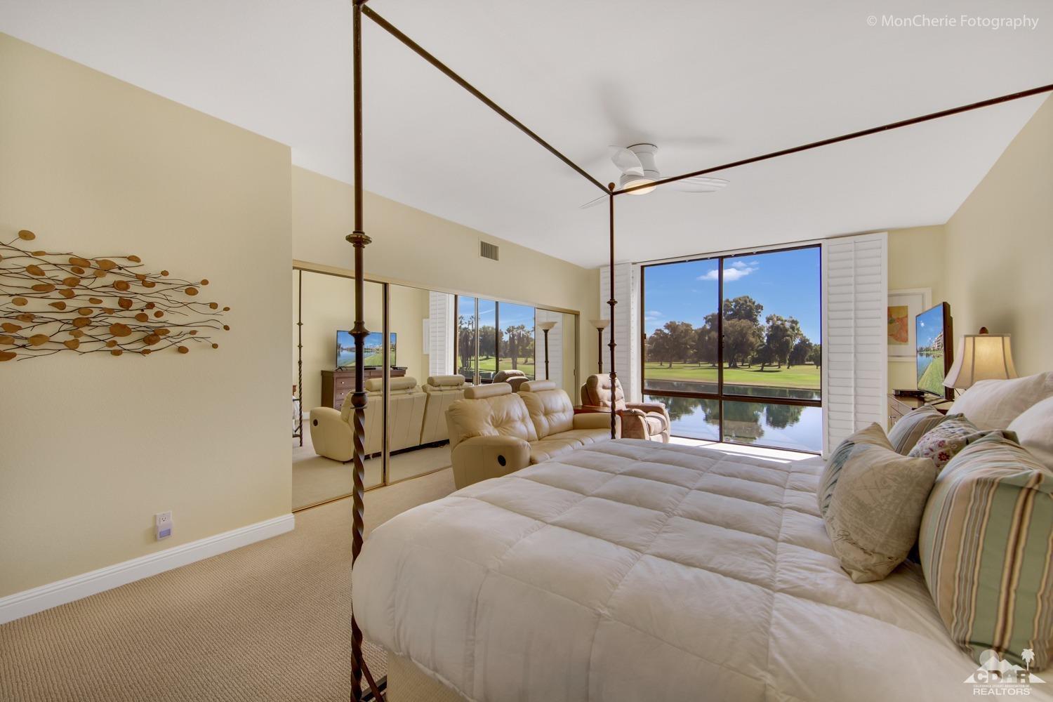 910 Island Drive, Unit 211 Rancho Mirage, CA 92270 - Photo 4 of 38 a bedroom with a bed a large window and flat screen tv