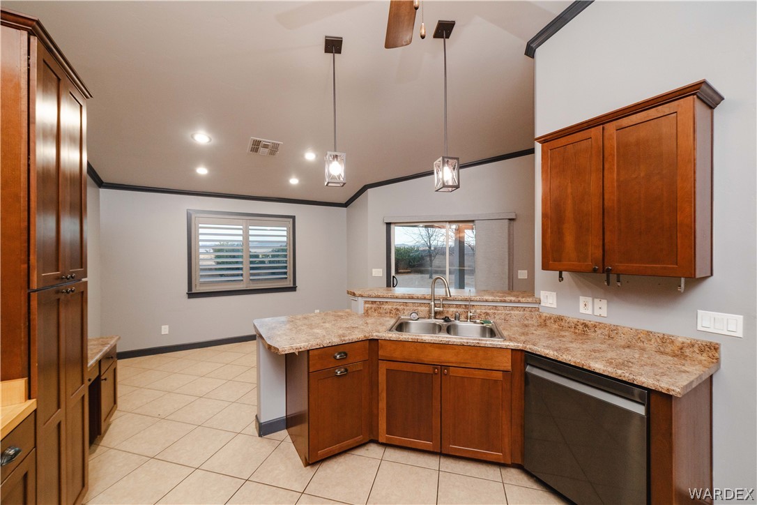 3374 Roma Road Kingman, AZ 86401 - Photo 8 of 64 Kitchen with a peninsula, stainless steel dishwasher, wood finish cabinets, lofted ceiling, and hanging light fixtures