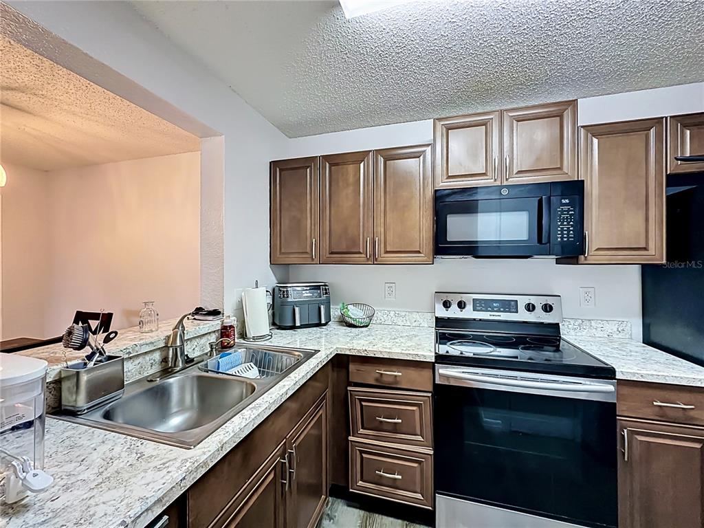 3705 Southwest 27th Street, Unit 922 Gainesville, FL 32608 - Photo 8 of 34 a kitchen with granite countertop a sink stove and microwave