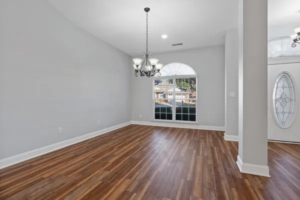 a view of a room with wooden floor fan and windows