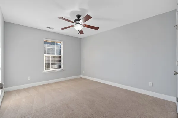 an empty room with windows and fan