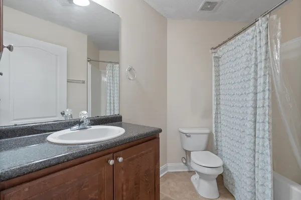 a bathroom with a granite countertop sink a toilet and a shower