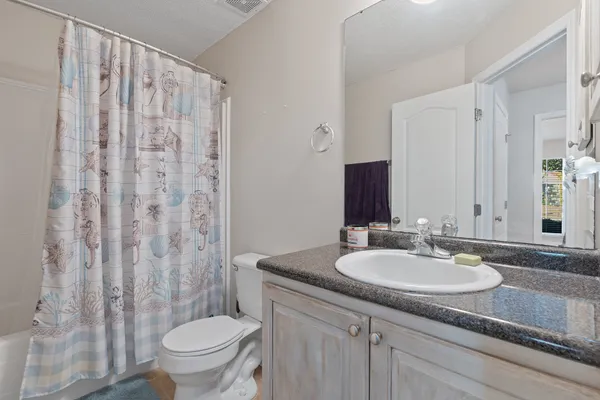 a bathroom with a granite countertop sink a toilet and a mirror
