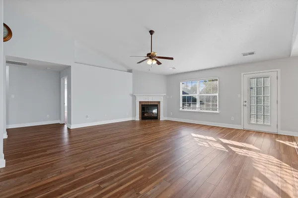 a view of an empty room with wooden floor and a window