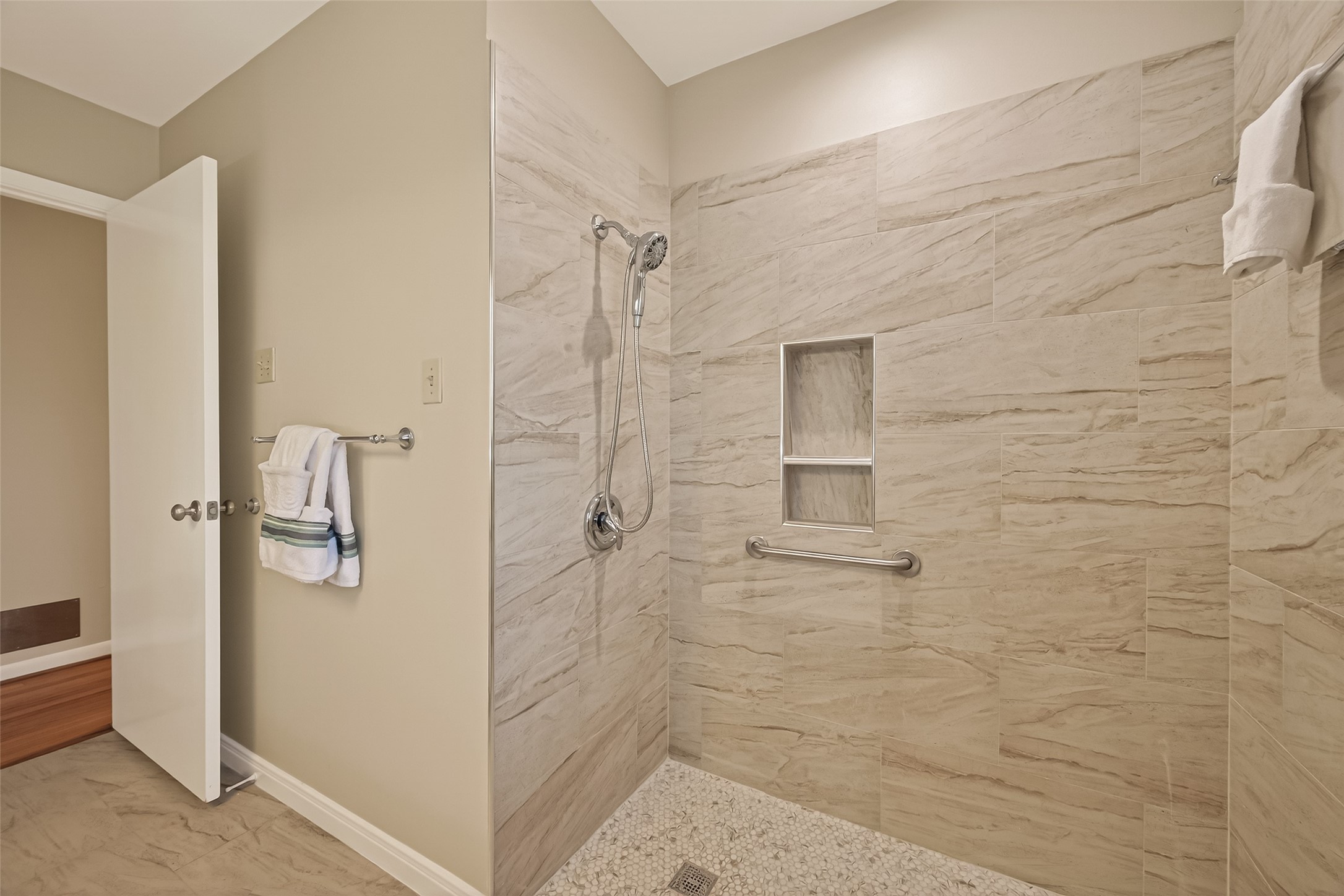 5646 Hazen Street Houston, TX 77081 - Photo 31 of 43 The bathroom has a generously sized walk-in shower, polished with beige tiles with a built-in niche, and a safety grab bar.