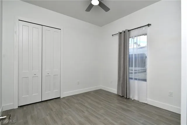 an empty room with wooden floor cabinet and windows